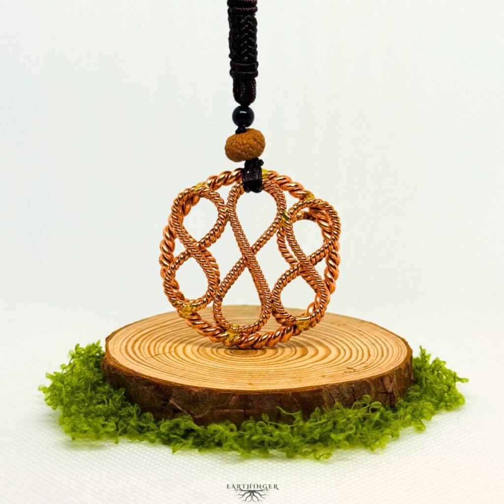 Handgefertigter Triple Infinity Tensor-Ring aus Kupfer zur Erdung und energetischen Heilung, dargestellt auf natürlicher Holzscheibe