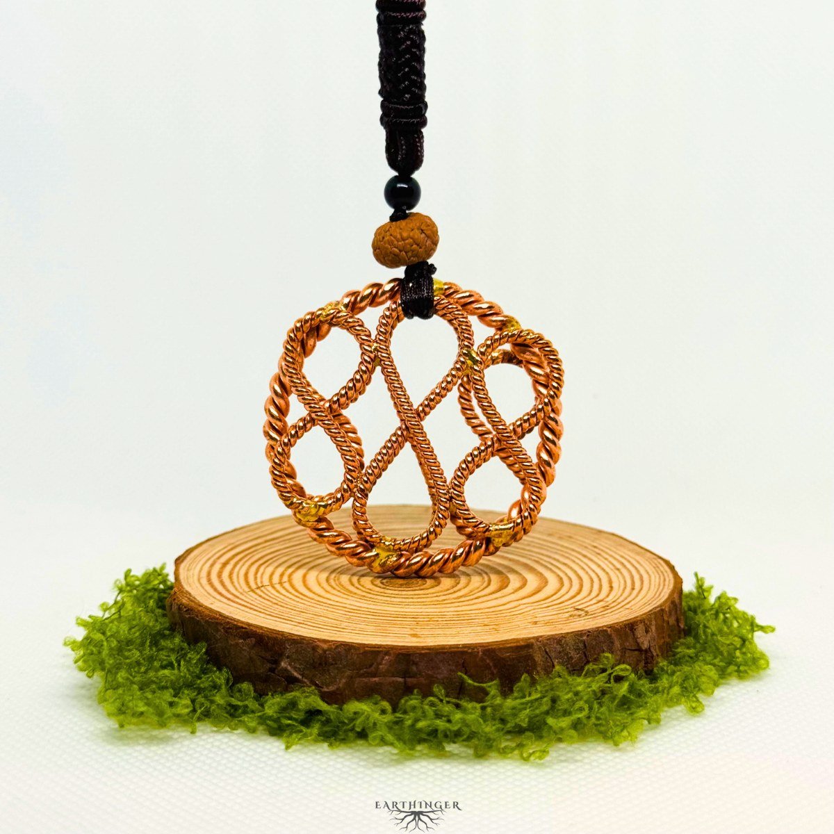 Handgefertigter Triple Infinity Tensor-Ring aus Kupfer zur Erdung und energetischen Heilung, dargestellt auf natürlicher Holzscheibe